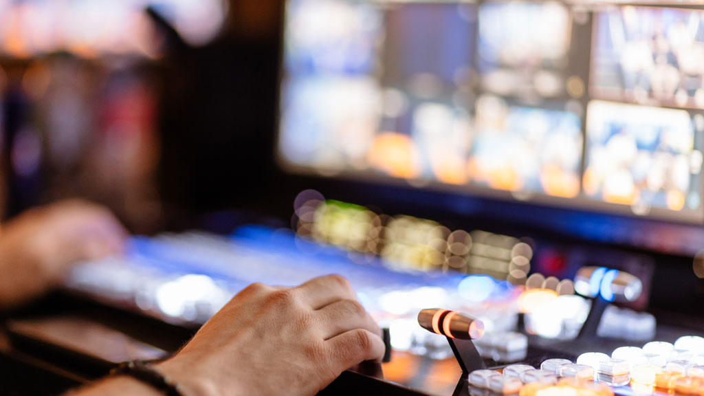 Technicienne audiovisuelle comparant deux caméras professionnelles sur établi d'atelier