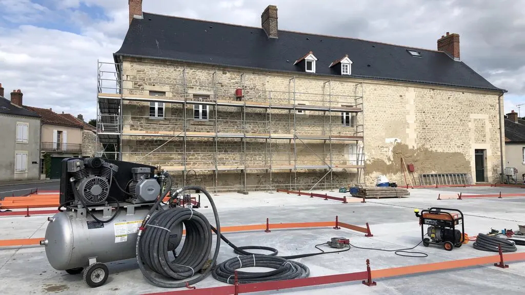 Vue d'ensemble d'un chantier de décapage de façade avec compresseur, échafaudage et équipement professionnel installé devant un bâtiment ancien
